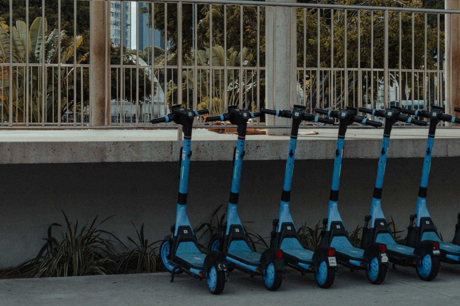 Fileira de patinetes elétricos azuis estacionados ao ar livre, representando a mobilidade urbana compartilhada.
