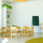 Sala de educação infantil colorida, com mesas, cadeiras e materiais educativos organizados.