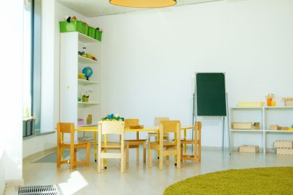 Sala de educação infantil colorida, com mesas, cadeiras e materiais educativos organizados.