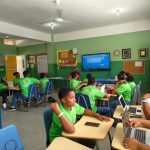 Estudantes participam de uma aula colaborativa usando laptops em uma sala de aula.