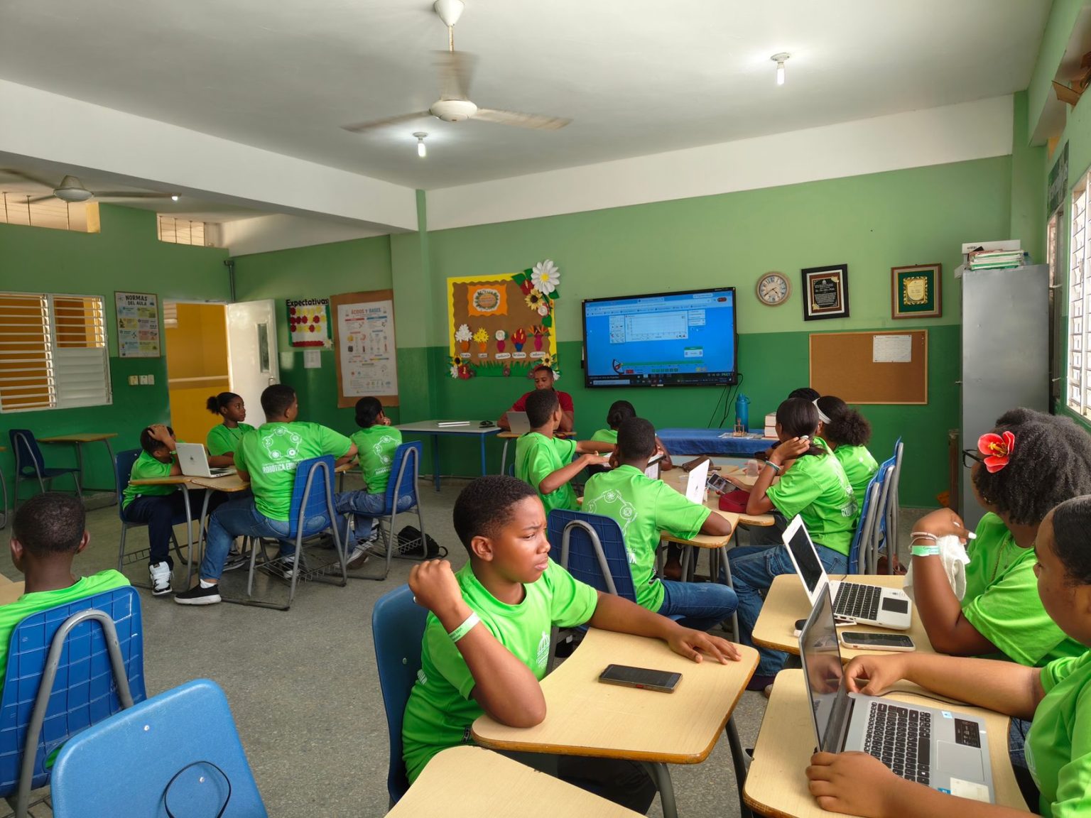 Estudantes participam de uma aula colaborativa usando laptops em uma sala de aula.