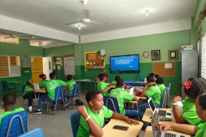 Estudantes participam de uma aula colaborativa usando laptops em uma sala de aula.