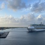 Navio de cruzeiro se aproxima de um píer em um dia nublado.