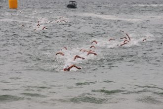 Grupo de nadadores participa de uma prova de natação em mar aberto.