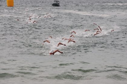 Grupo de nadadores participa de uma prova de natação em mar aberto.